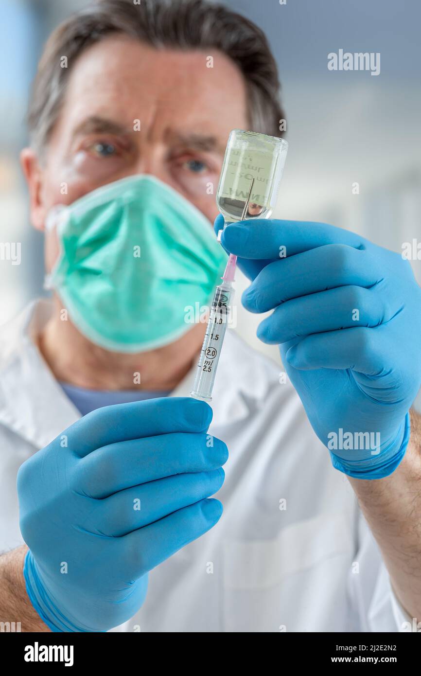 Der Arzt füllt eine Spritze mit Impfstoff auf verschwommenem Hintergrund. Stockfoto