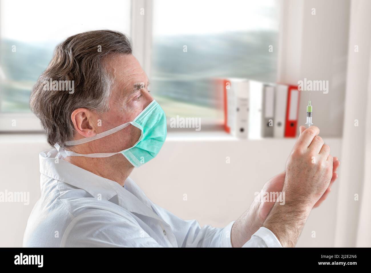 Der Arzt füllt eine Spritze mit Impfstoff auf verschwommenem Hintergrund. Stockfoto