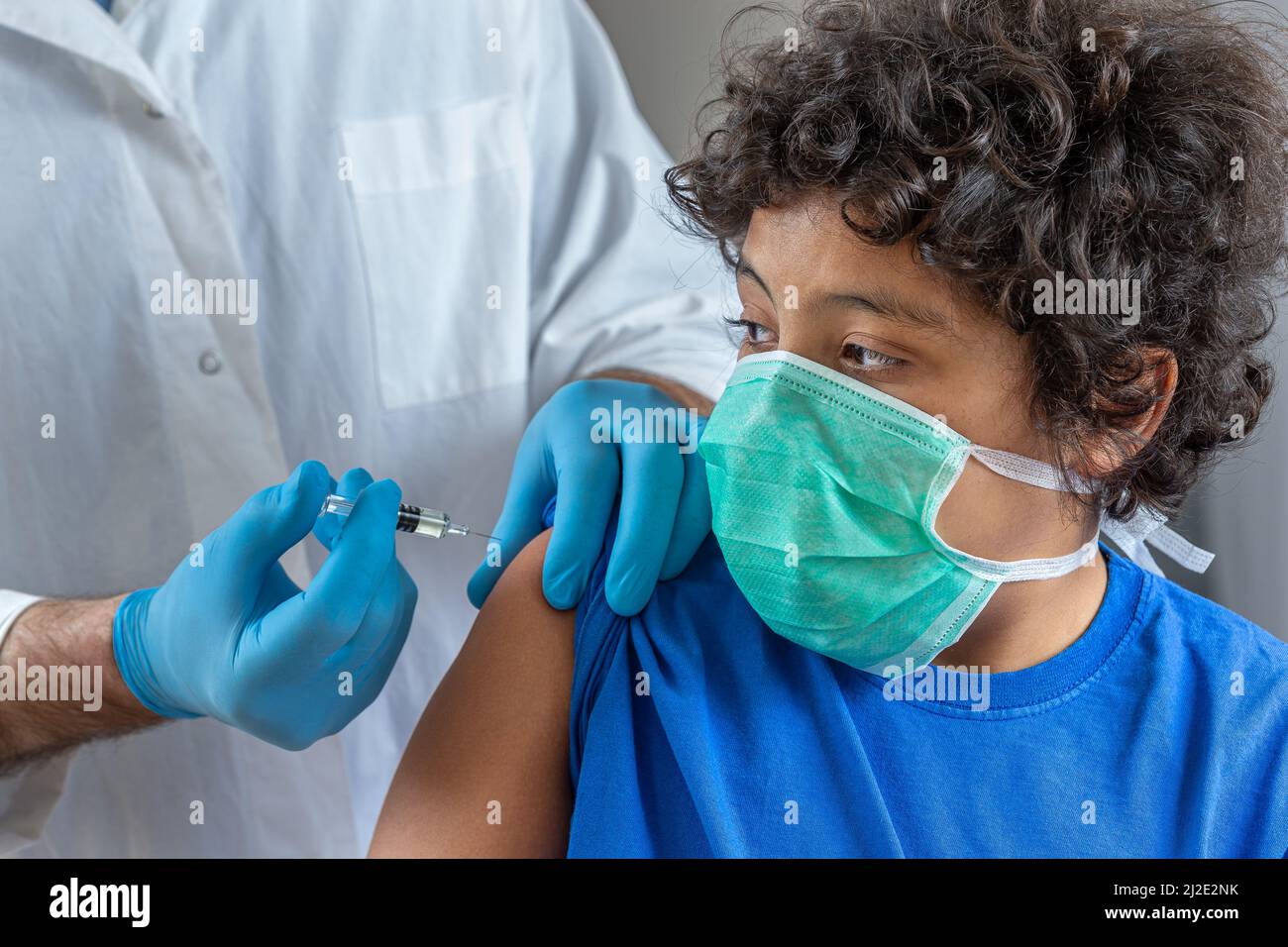 Männlicher Arzt in schützenden Gesichtsmaske Latexhandschuhe geben intramuskuläre Impfung geschützten Arm des Patienten Stockfoto