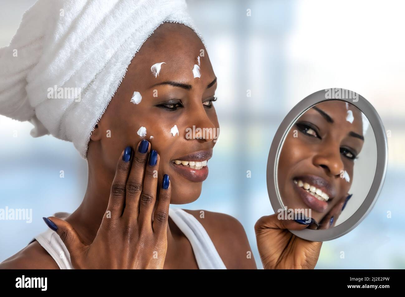 Junge Frau vor einem Badezimmerspiegel, der Creme auf einen roten Noppen setzt. Beauty-Hautpflege und Wellness-Morgenkonzept. Stockfoto