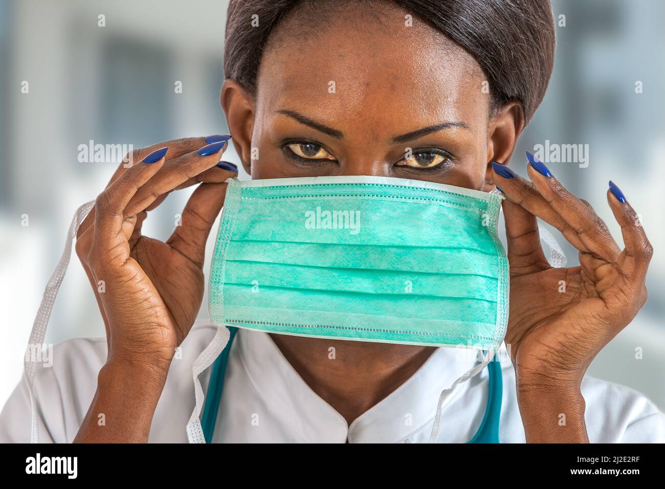 Weibliche amerikanische afrikanische Ärztin, Krankenschwester Frau trägt medizinischen Mantel mit Stethoskop und Maske. Stockfoto
