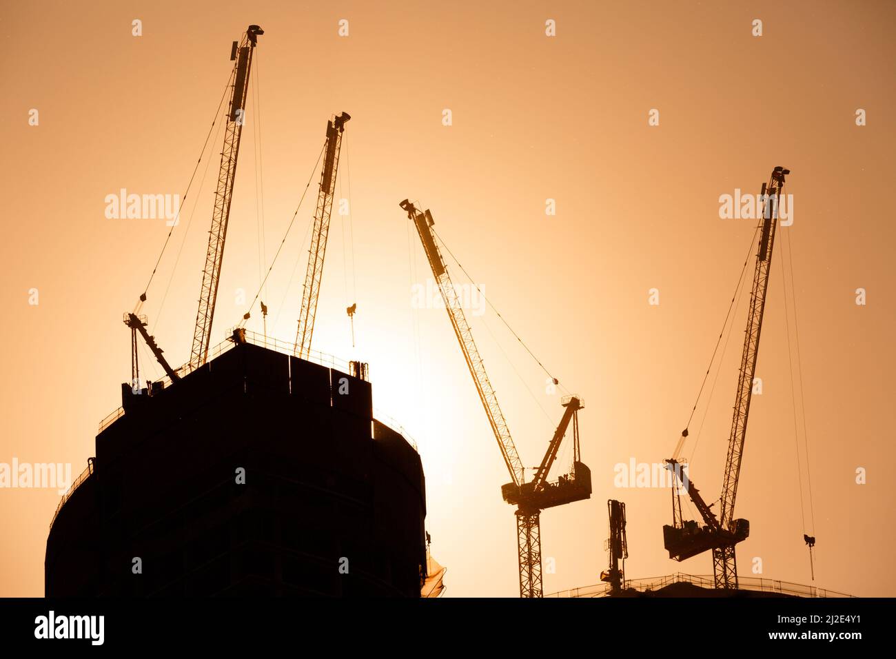 Turmdrehkrane im Sonnenlicht. Die Silhouette eines Turmdrehkrans. Bau eines Wolkenkratzers. Kranausleger Stockfoto