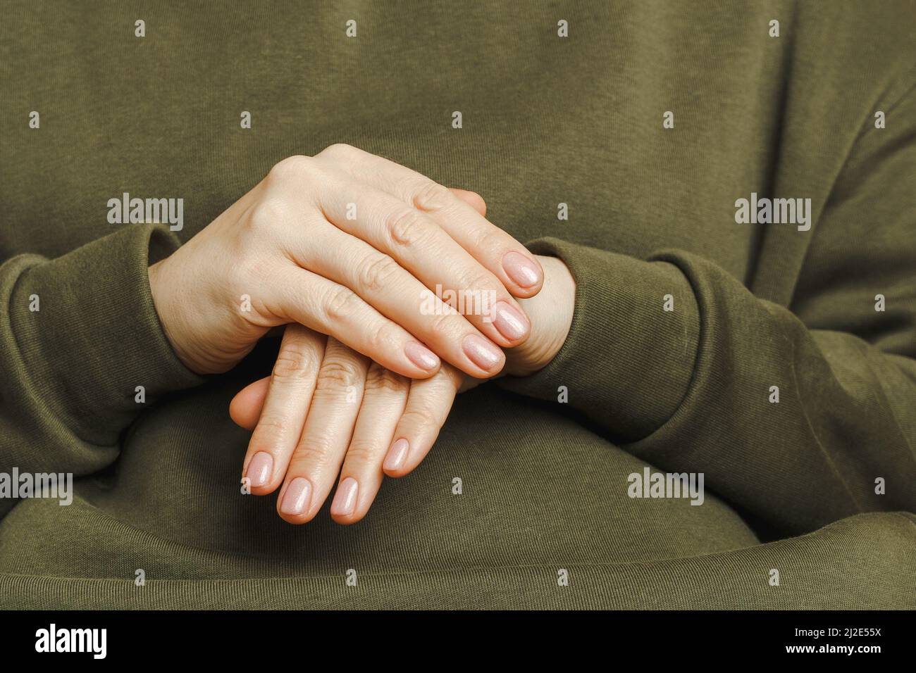 Damenhände mit perfekter Maniküre. Hände eines Mädchens in einem grünen Hoodie Nahaufnahme Stockfoto