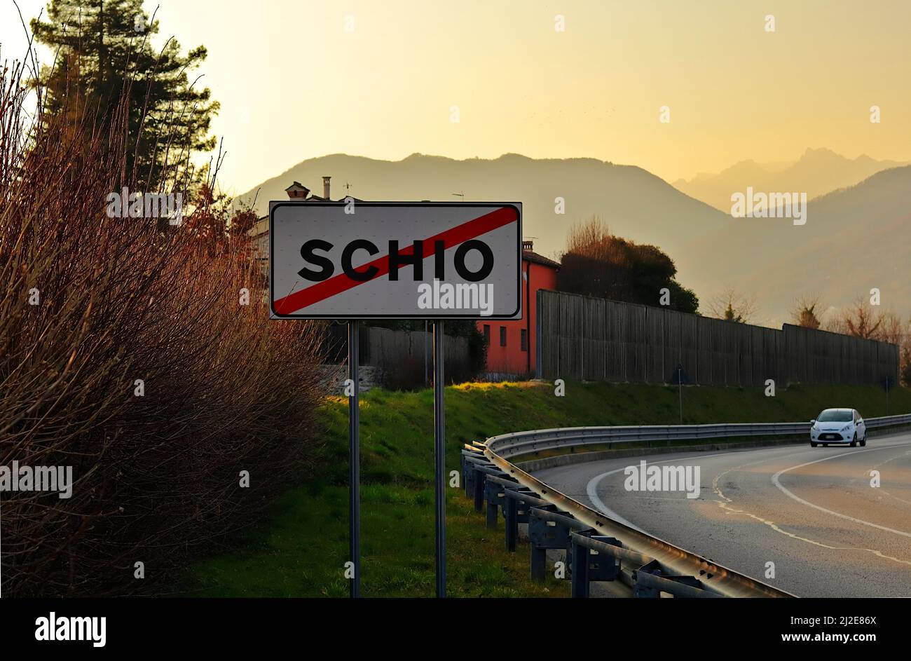 Inschrift „Schio“ (Stadt in der Provinz Vicenza) auf einem Verkehrsschild, das das Ende der Stadt anzeigt. Im Hintergrund die Kleinen Dolomiten Stockfoto