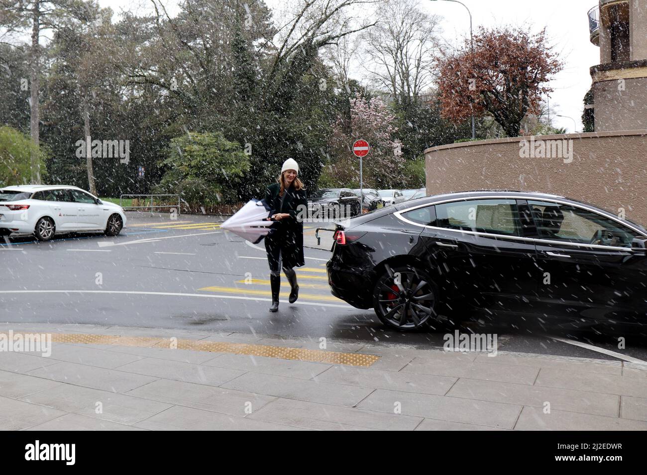 Genf, Schweiz, 2022-04-01 Frau überquert die Straße durch den Schnee. Der erste Apriltag hat mit winterlichen Wetter begonnen. Kredit: marcio cimatti/Alamy Live Nachrichten Stockfoto