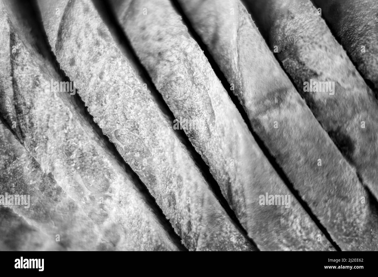 Scheiben von weißem Brot Nahaufnahme als Hintergrund. Grauer Hintergrund der rauhen strukturierten Oberfläche gehackte Stücke Laib von natürlichen Bio-Lebensmitteln. Draufsicht. Getönte i Stockfoto