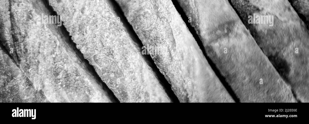 Scheiben von weißem Brot Nahaufnahme als Hintergrund. Grauer Hintergrund der rauhen strukturierten Oberfläche gehackte Stücke Laib von natürlichen Bio-Lebensmitteln. Draufsicht. Getönte i Stockfoto