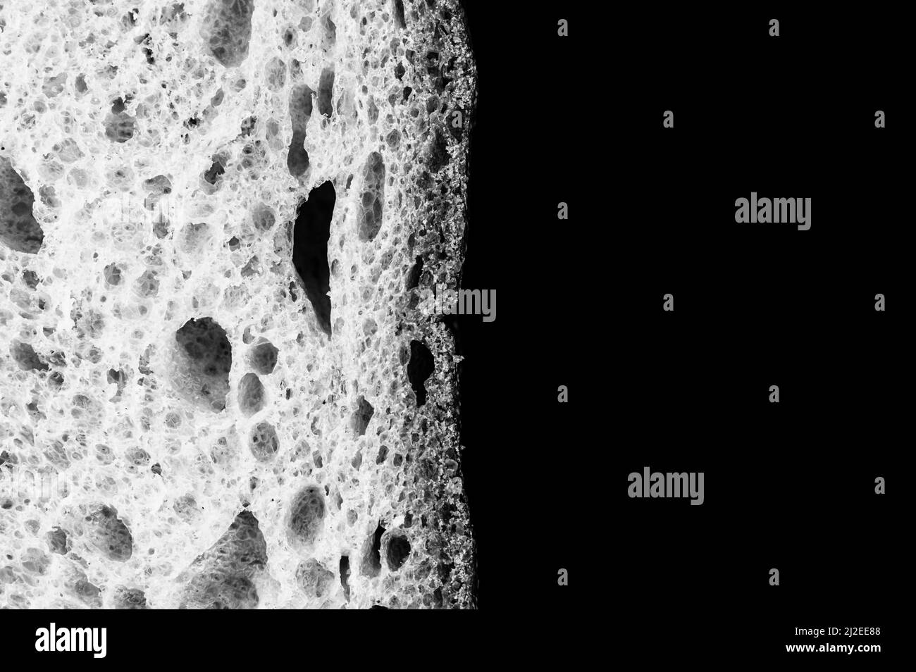 Scheibe Weißbrot Nahaufnahme isoliert auf schwarzem Hintergrund. Grau rau strukturierte Oberfläche gehackt Stück Laib von Lebensmitteln mit Löchern. Draufsicht. Abstract Konz Stockfoto