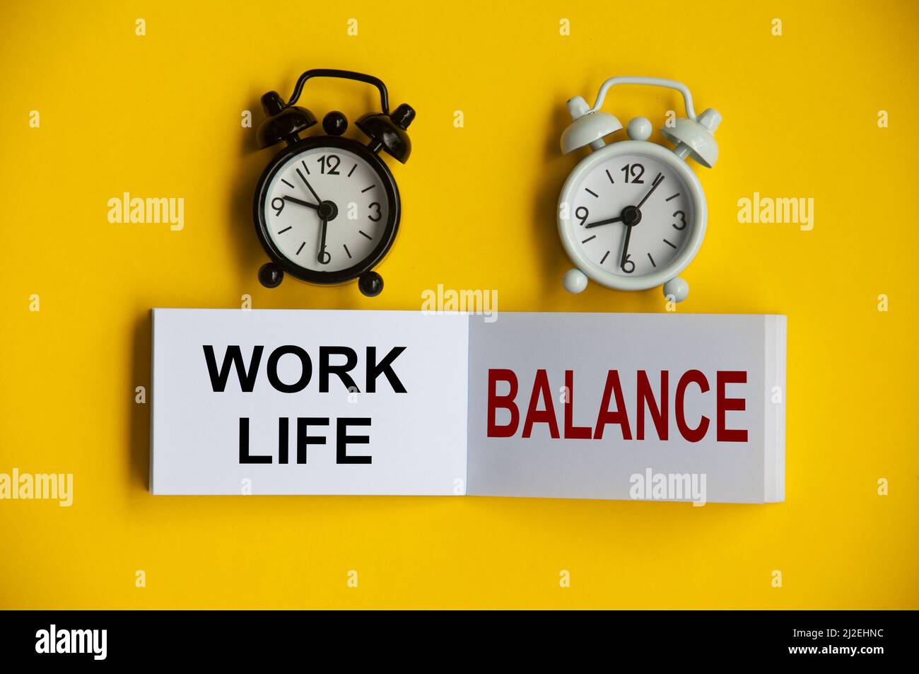 Work Life Balance Text auf Notizblock mit Wecker auf gelbem Hintergrund. Konzeptionell Stockfoto