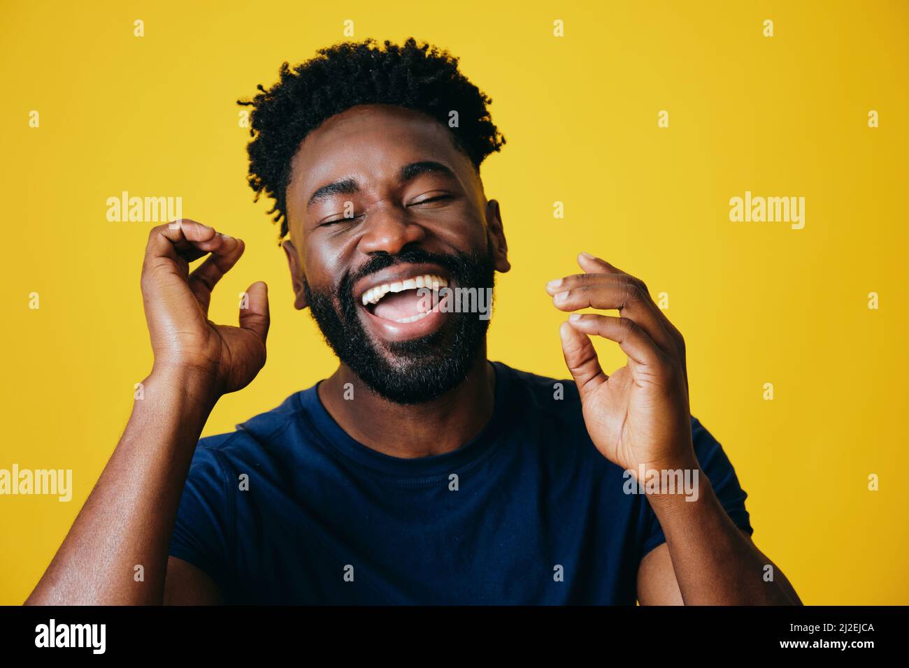 Porträt eines verspielten Afro-Mannes mit geöffneten Händen vor gelbem Hintergrund Stockfoto