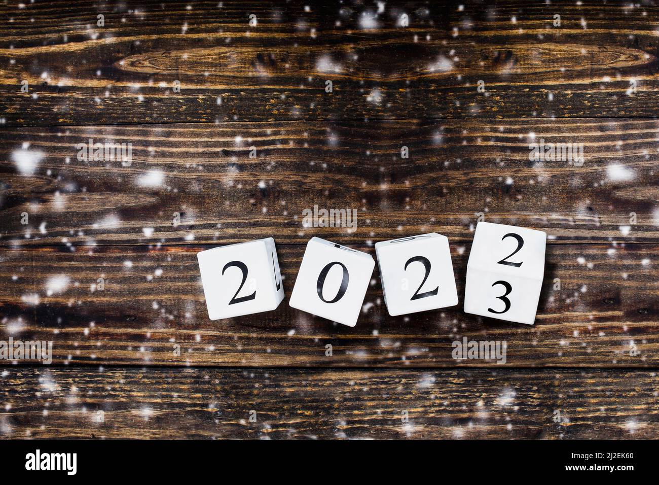 Weiße Holzkalenderblöcke, die den Jahreswechsel 2022 bis 2023 drehen. Ansicht von der Tischplatte mit herabgefallener Schneedecke. Stockfoto