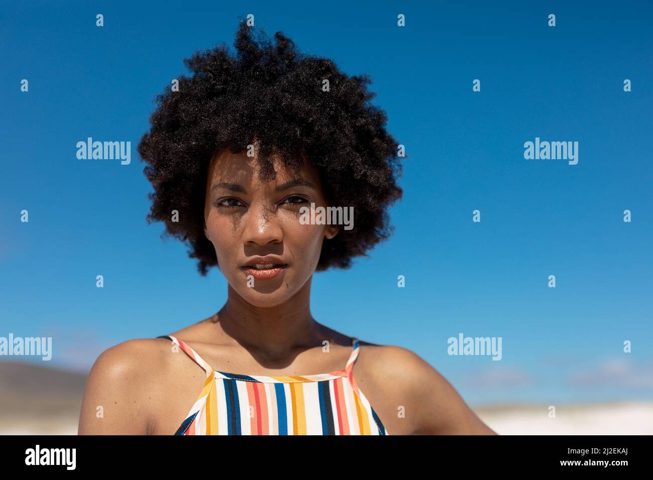 Porträt einer selbstbewussten jungen afroamerikanischen Frau mit Afro-Frisur gegen blauen Himmel Stockfoto