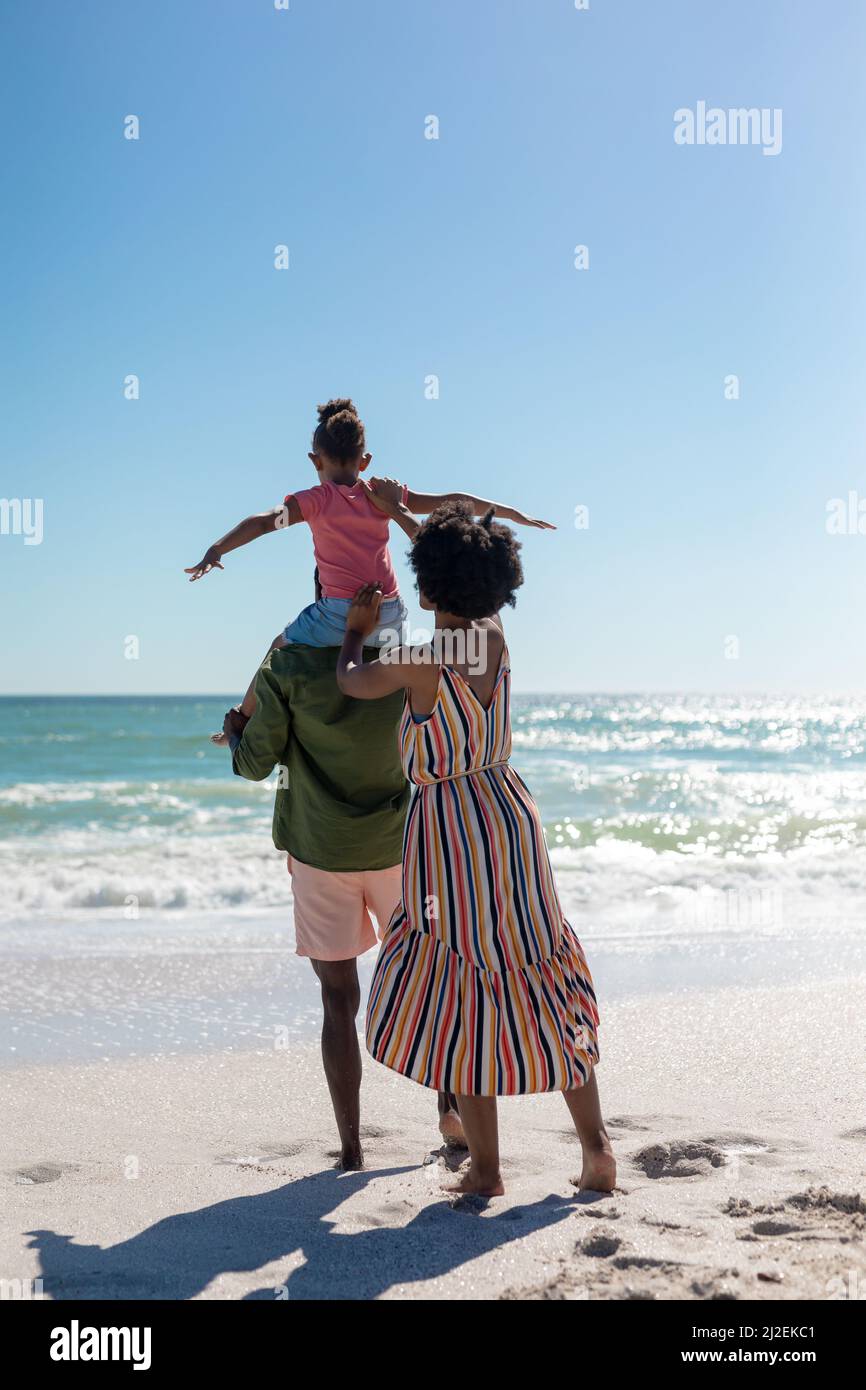 afroamerikanische Frau, die ihre Tochter unterstützt und am Strand auf den Schultern ihres Vaters sitzt Stockfoto