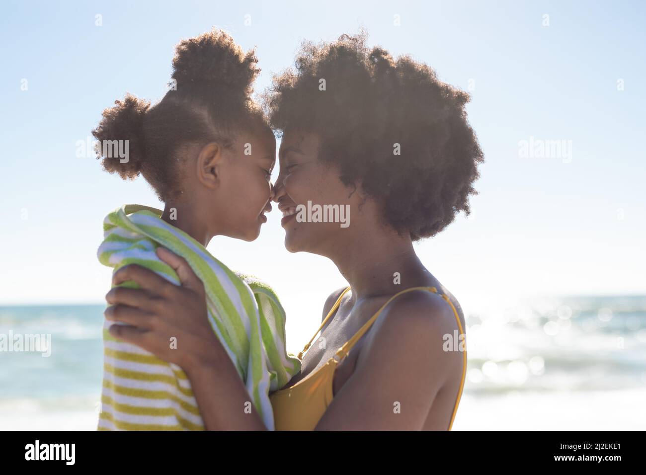 Seitenansicht der glücklichen afroamerikanischen Mutter und Tochter, die am Strand Nasen reiben Stockfoto