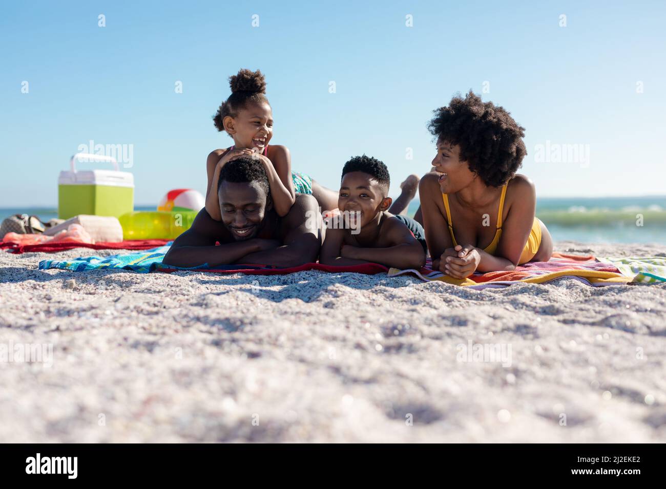 Glückliche afroamerikanische Familie, die am sonnigen Tag am Strand auf einem Handtuch lag Stockfoto