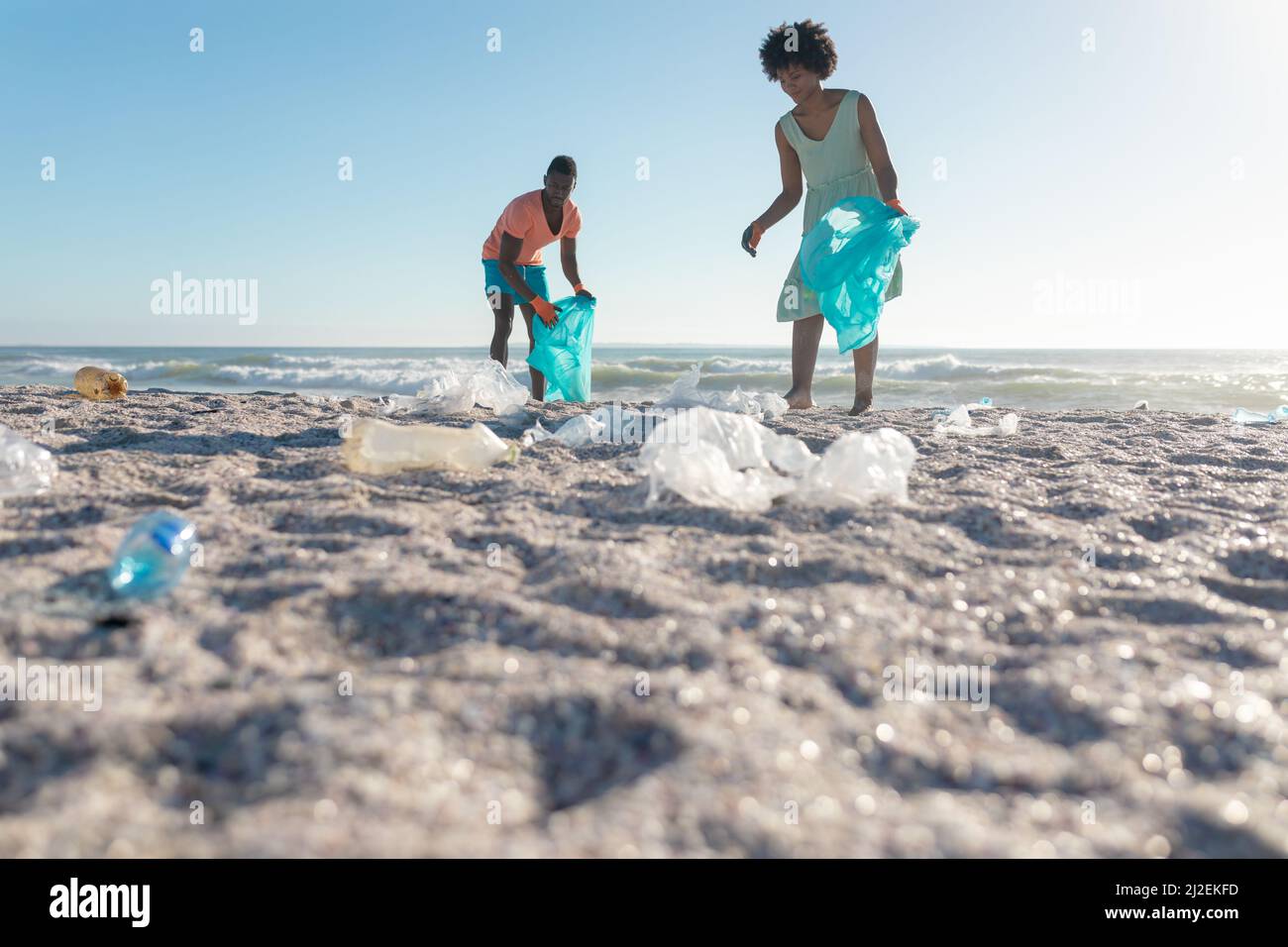 Oberflächennahe Ansicht des afroamerikanischen Paares, das am sonnigen Tag Müll am Strand sammelt Stockfoto