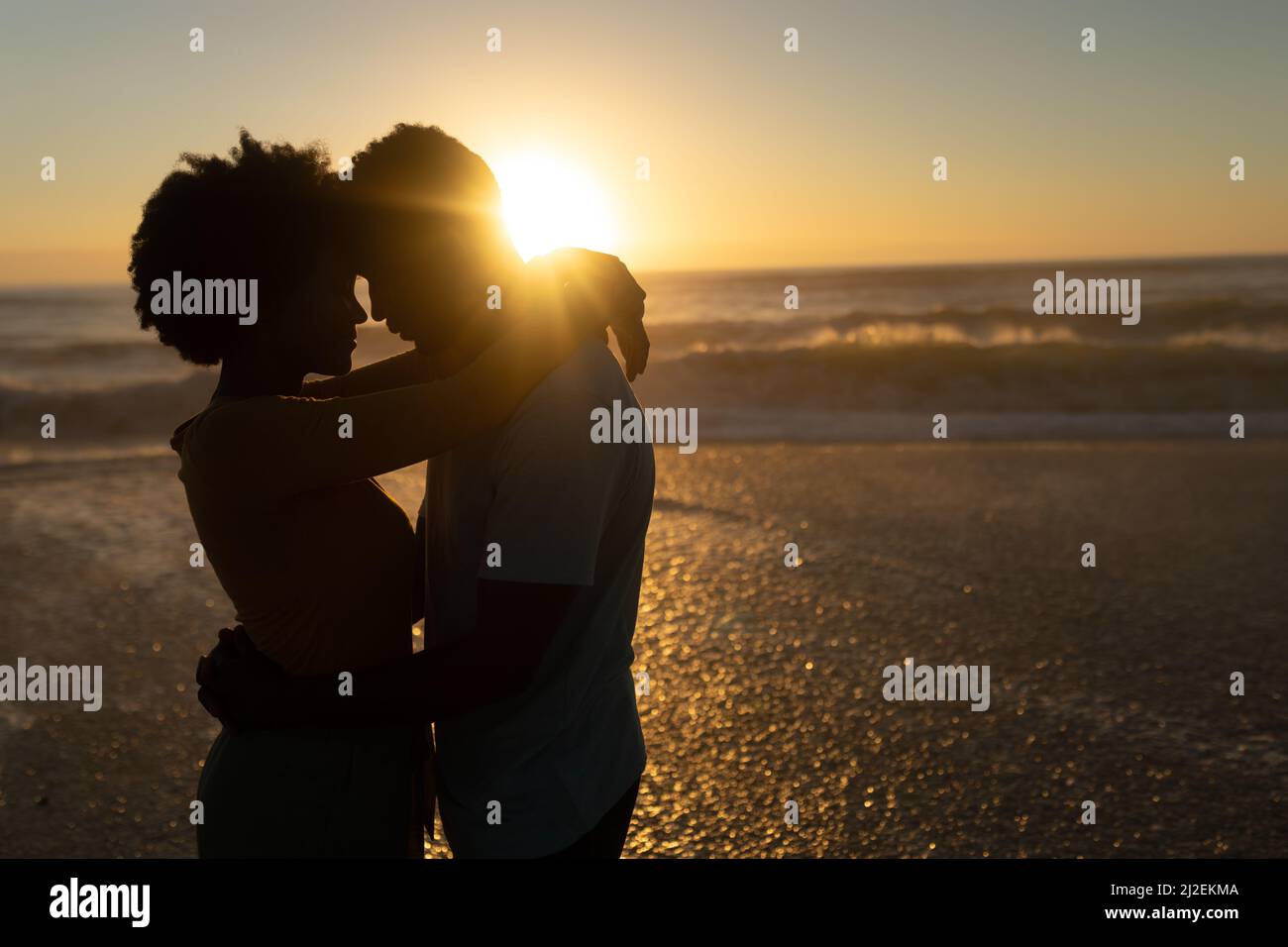 Romantisches afroamerikanisches Paar, das während des Sonnenuntergangs gemeinsam am Strand Freizeit verbringt Stockfoto