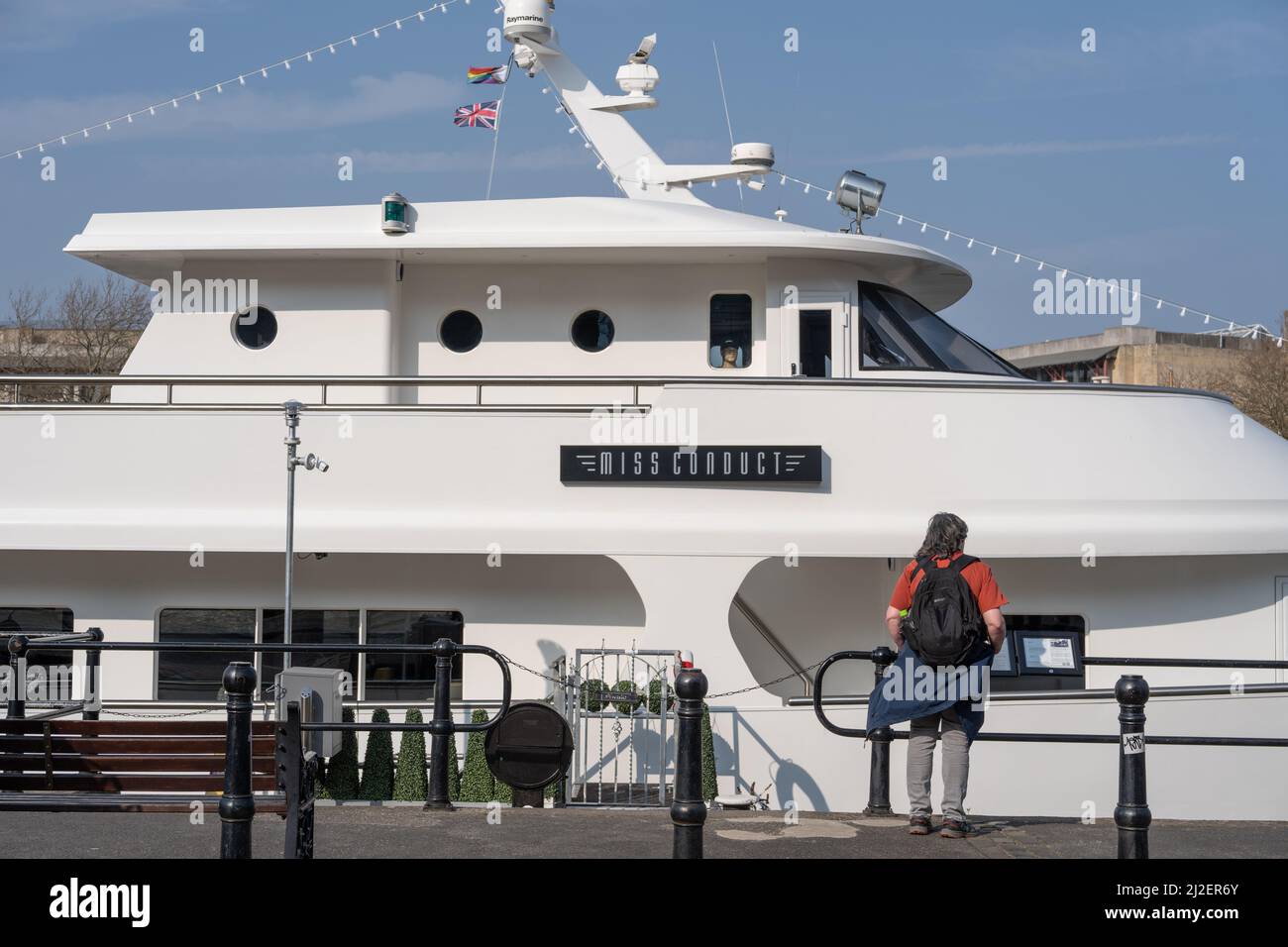 Ein Passant schaut auf eine private Luxusyacht, die im Hafen vor Anker liegt. Bristol, Großbritannien. Stockfoto