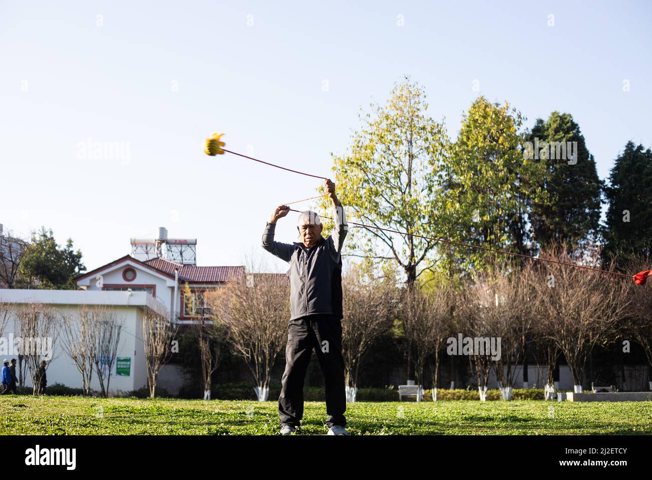 Älterer Mann, der morgens in einem Park Poi spinnt Stockfoto