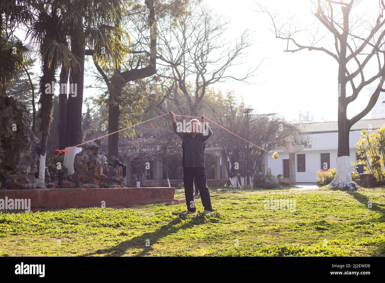 Älterer Mann, der morgens in einem Park Poi spinnt Stockfoto