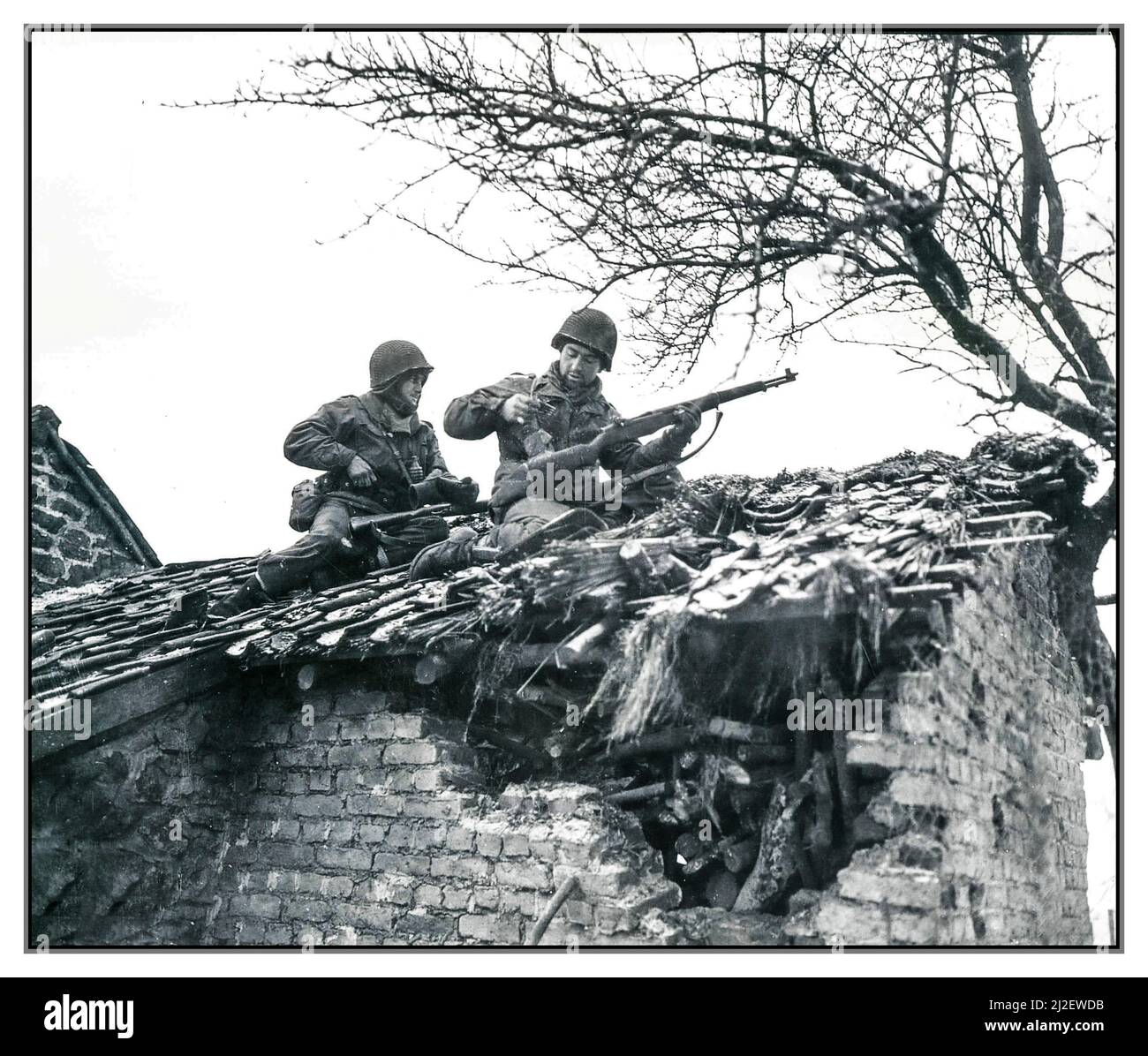 KAMPF UM DIE AUSBUCHTUNG S/SGT. Urban Minicozzi und PFC. Andy Masiero hält an, um nachzuladen, während Scharfschützen das Dach eines Gebäudes in Beffe, Belgien, bilden. 1. Bataillon, 290. Infanterie-Regiment, 75. Infanterie-Division.“ Fotograf: Corrado Datum 7. Januar 1945 Zweiter Weltkrieg Stockfoto