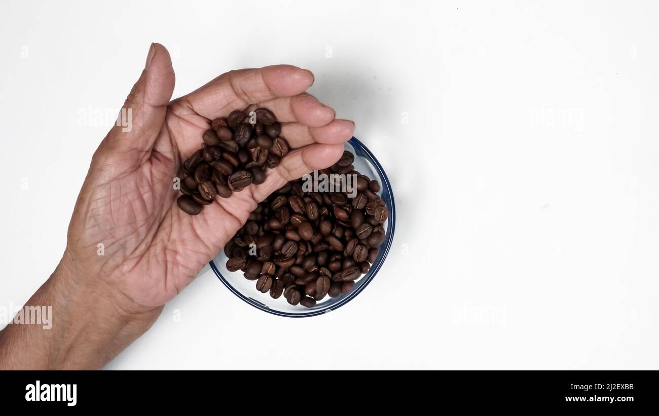 Hand Zeigt Kaffeebohnen Auf Der Hand, Kaffeebohnen In Glasschüssel, Isoliert Auf Weißem Hintergrund Stockfoto