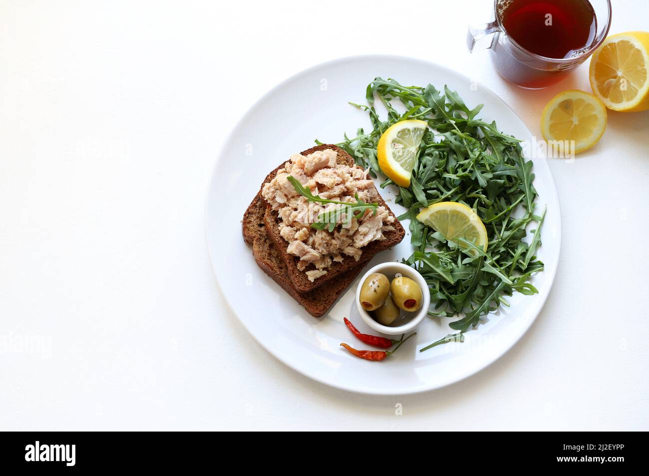 Scheiben Vollkornbrot mit Thunfisch, Zitrone und Gemüse isoliert auf weißem Hintergrund. Thunfisch-Vorspeise. Direkt darüber. Stockfoto