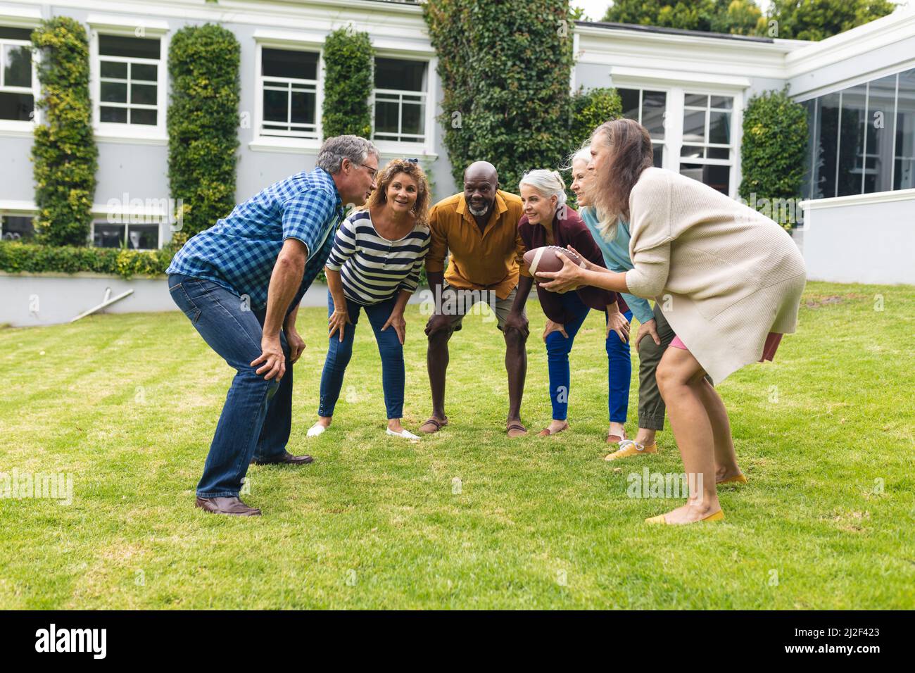 Mehrrassische ältere männliche und weibliche Freunde, die am Wochenende im Hinterhof Rugby spielen Stockfoto