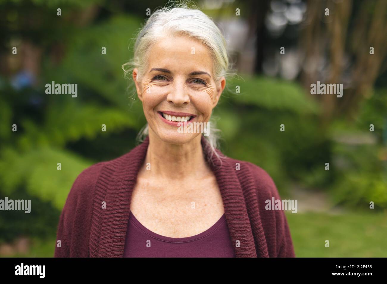 Porträt einer fröhlichen kaukasischen älteren Frau mit weißen Haaren im Hinterhof Stockfoto