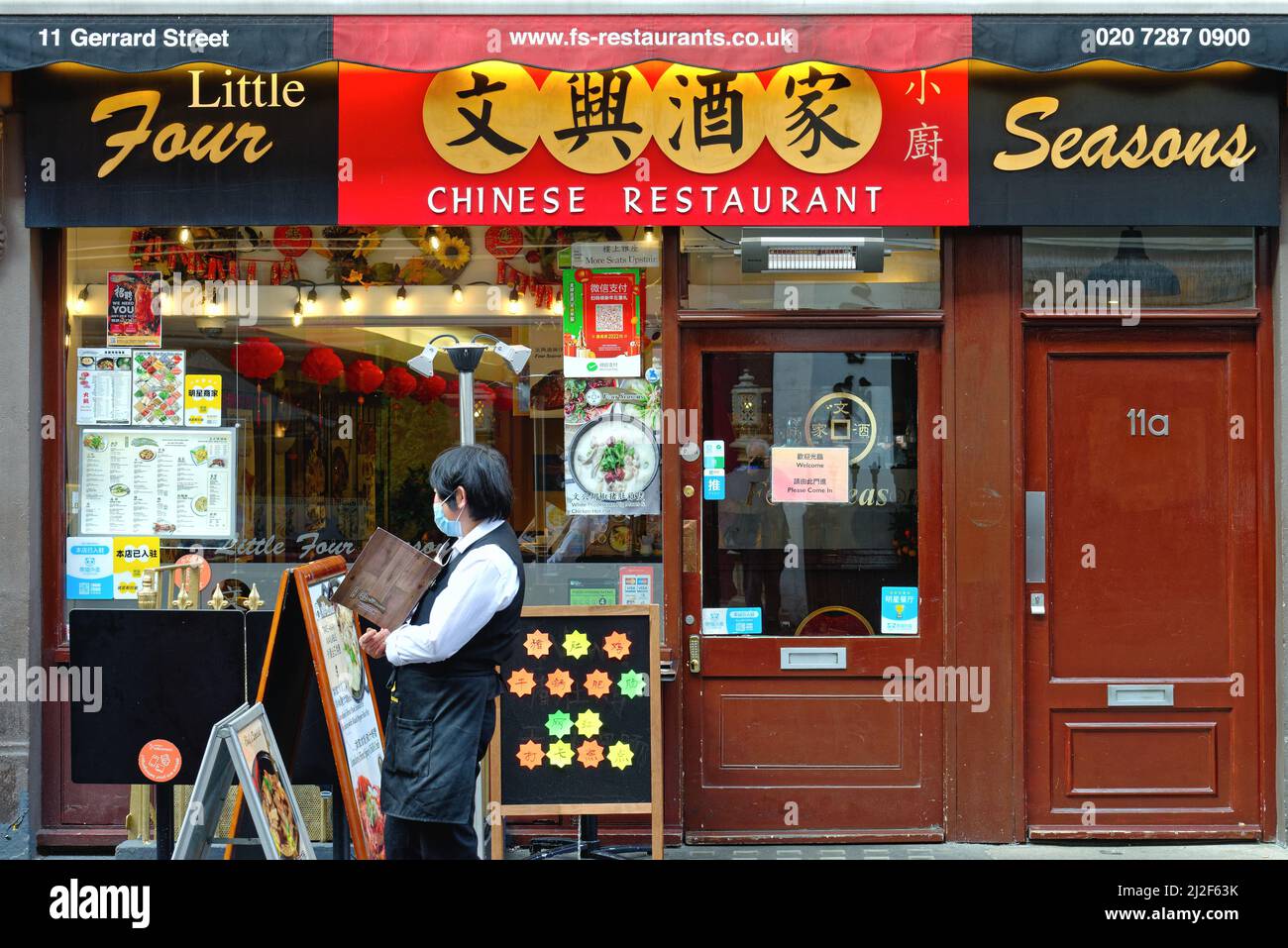 Außenansicht eines farbenfrohen chinesischen Restaurants mit einer Kellnerin, die nach Kunden sucht, Gerrard Street Chinatown Central London England UK Stockfoto
