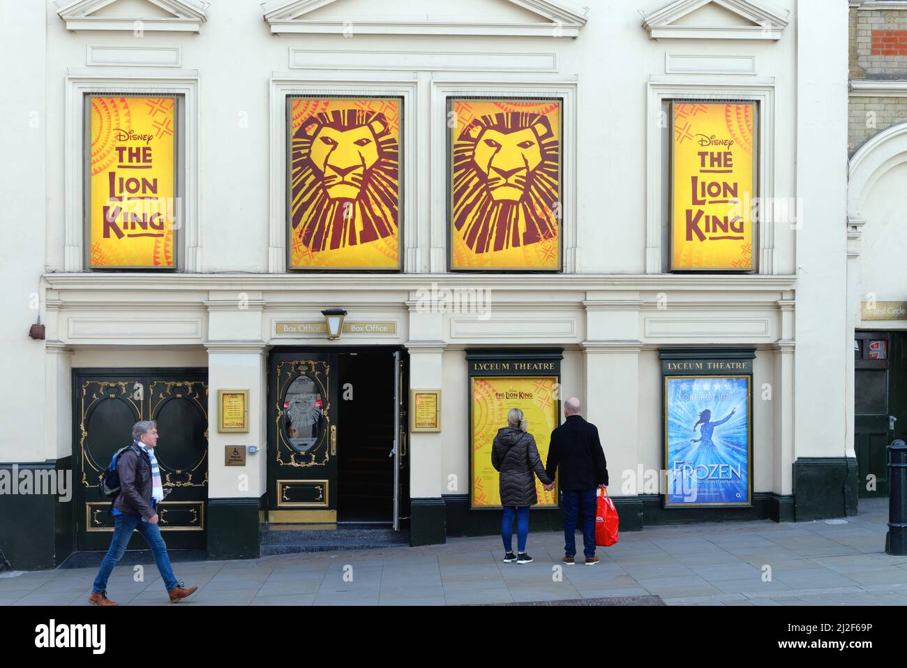 Außenansicht des Lyceum Theatre, das ein Paar zeigt, das Plakate für das Lion King Musical, Wellington Street Covent Garden London England, Großbritannien, ansieht Stockfoto