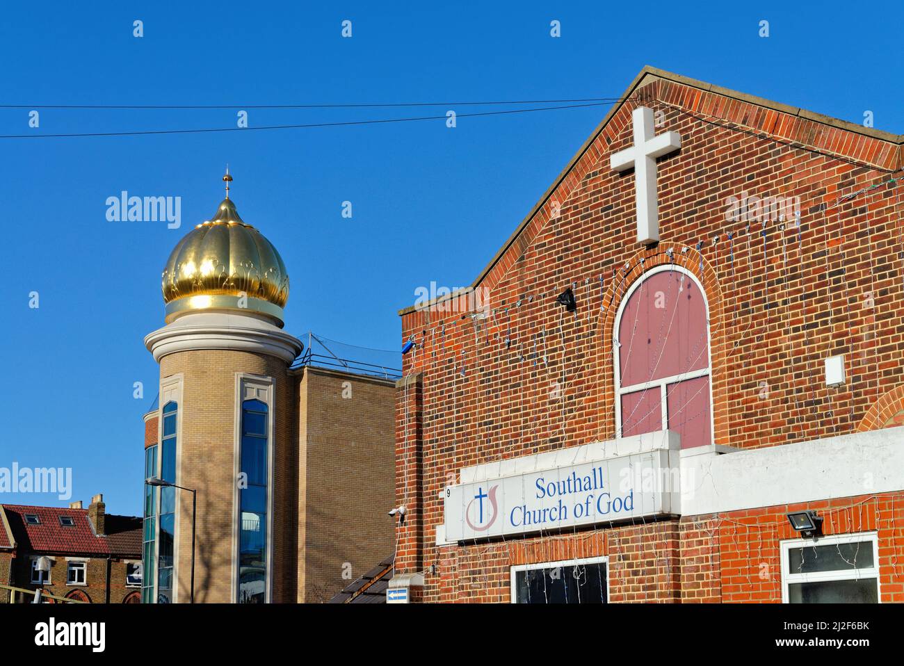 Der Gurdwara Guru Nanak Darber Sikh Tempel und die Southall Church of God Gebäude nebeneinander in Southall West London England Stockfoto