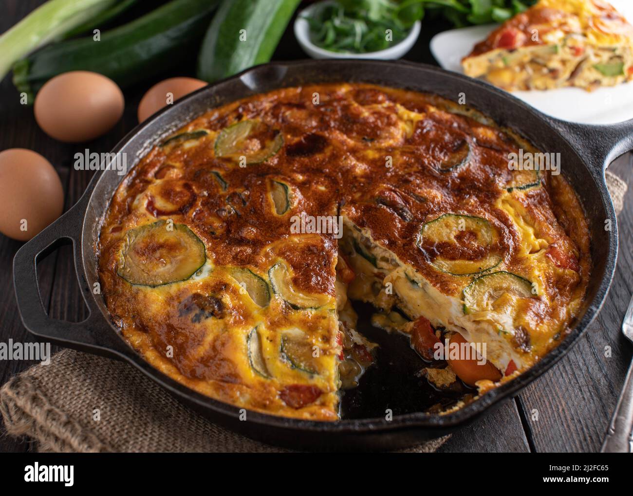Frittata mit Gemüse. Im Ofen gebacken und hausgemacht gekocht. Serviert in einer rustikalen gusseisernen Pfanne Stockfoto