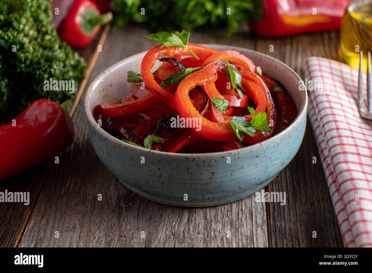 Gieße Olivenöl über einen gerösteten roten Paprikasalat Stockfoto