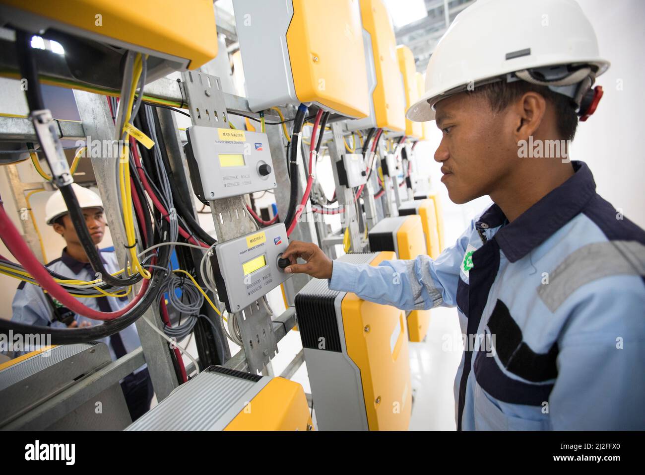 Ein Elektrotechniker betreibt Ausrüstung in einem Solarkraftwerk auf der Insel Karampuang, Indonesien, Asien. Stockfoto