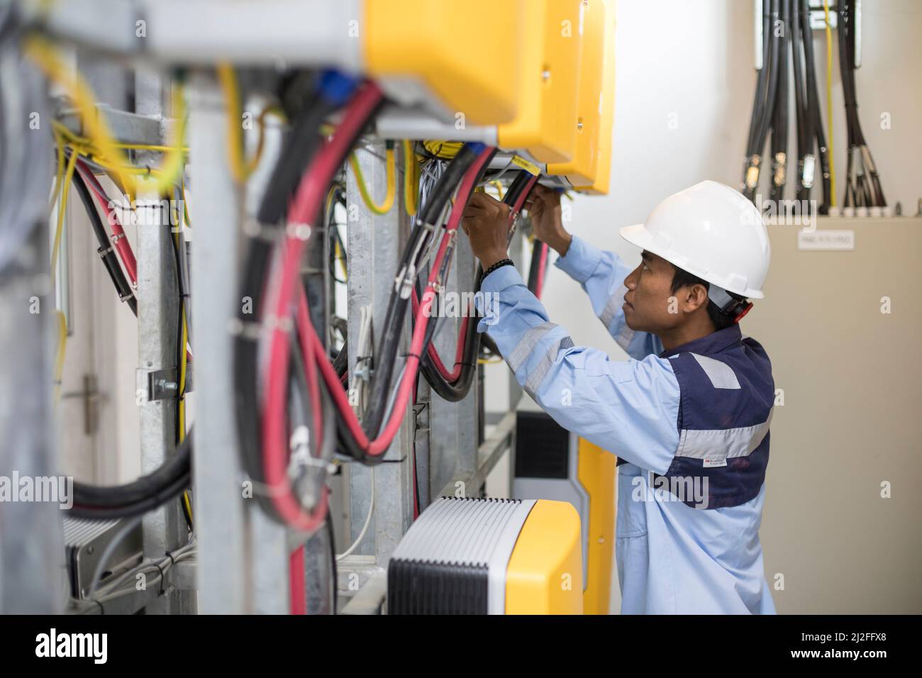 Ein Elektrotechniker betreibt Ausrüstung in einem Solarkraftwerk auf der Insel Karampuang, Indonesien, Asien. Stockfoto