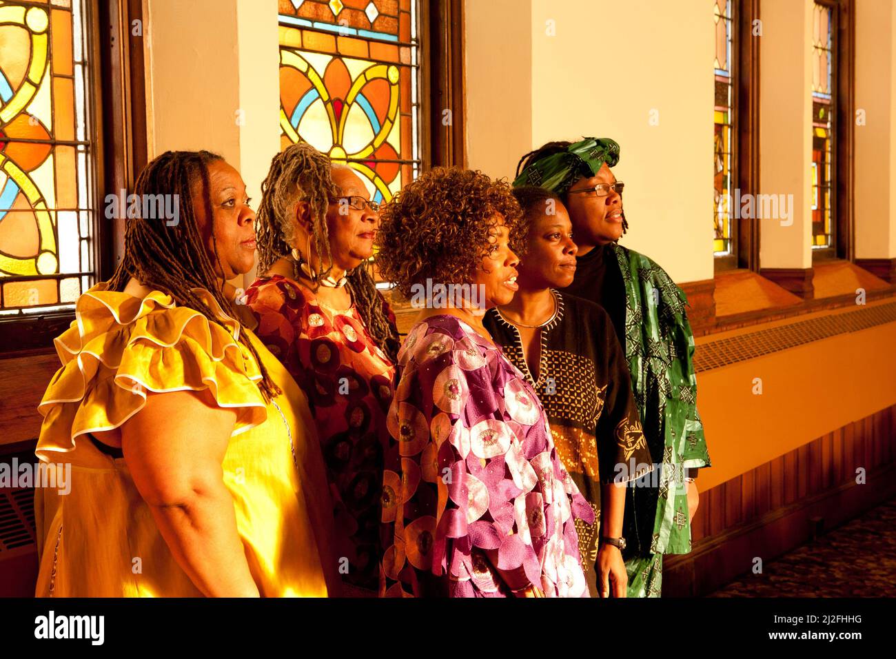 Drehort von bunt gekleideten älteren afrikanischen Frauen in einem die kirche blickt in die Morgensonne Stockfoto