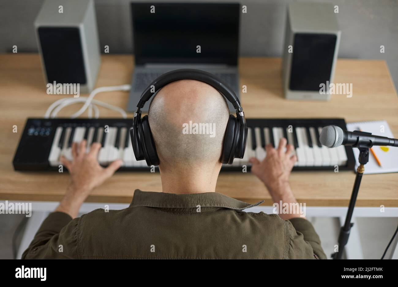 Professioneller männlicher Musiker kreiert einen neuen Song für Musikalbum, indem er Synthesizer im Studio spielt. Stockfoto
