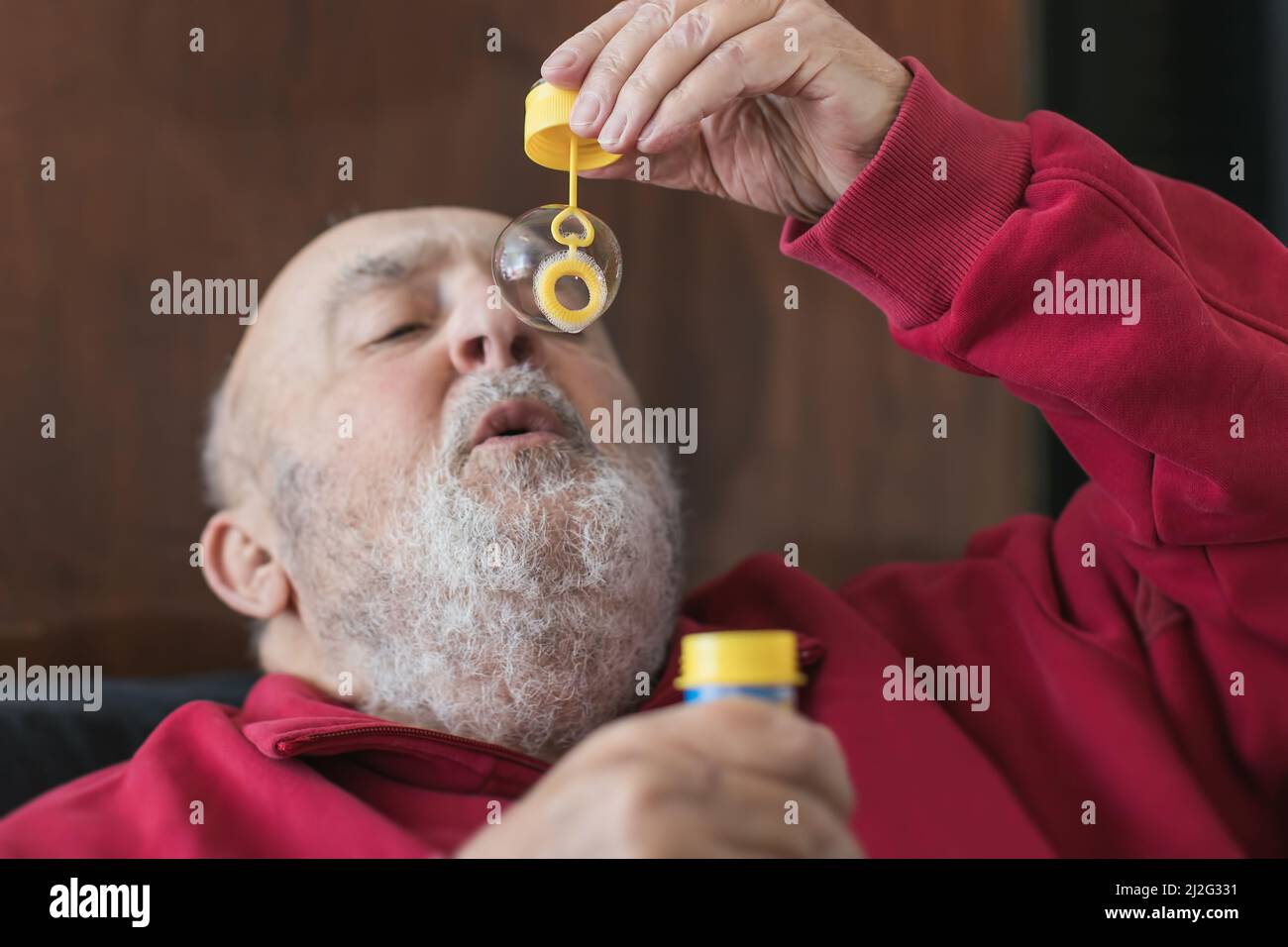 Älterer Mann bläst Seifenblasen Luftballons Stockfoto