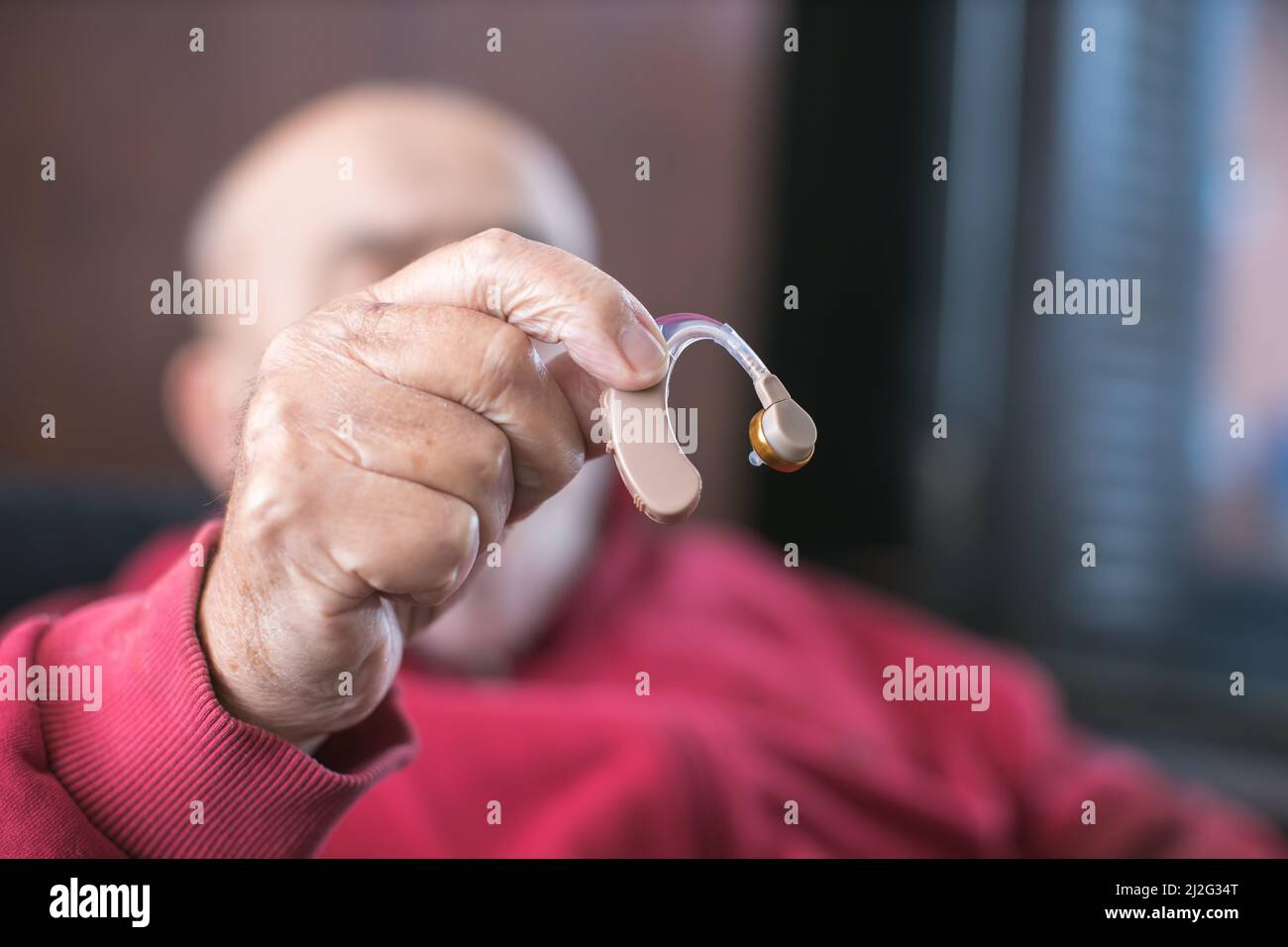 Älterer Mann, der Hörgerät in der Hand hält Stockfoto