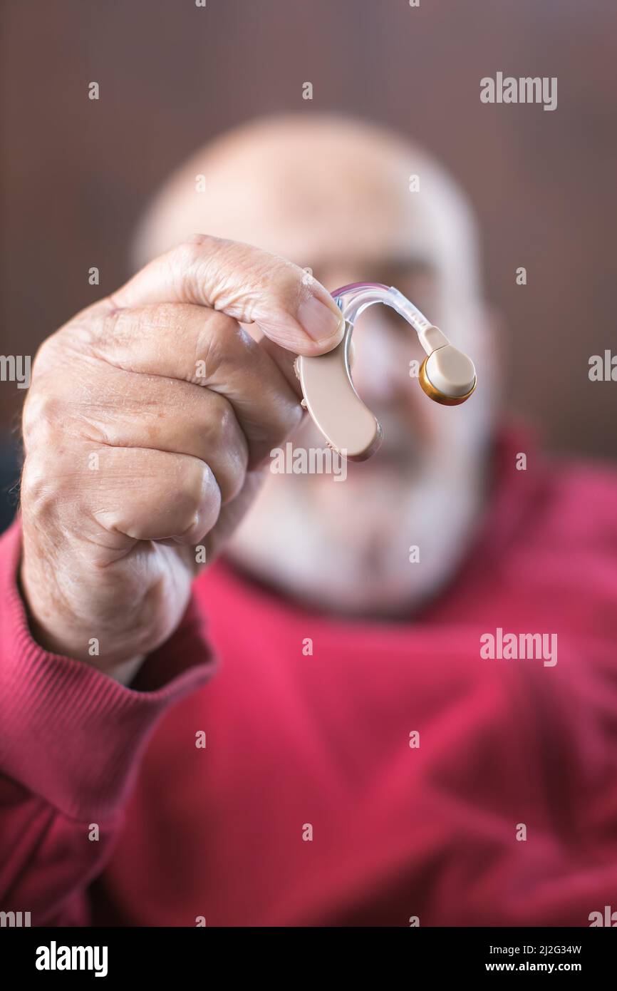 Alter Mann, der Hörgerät in der Hand hält Stockfoto