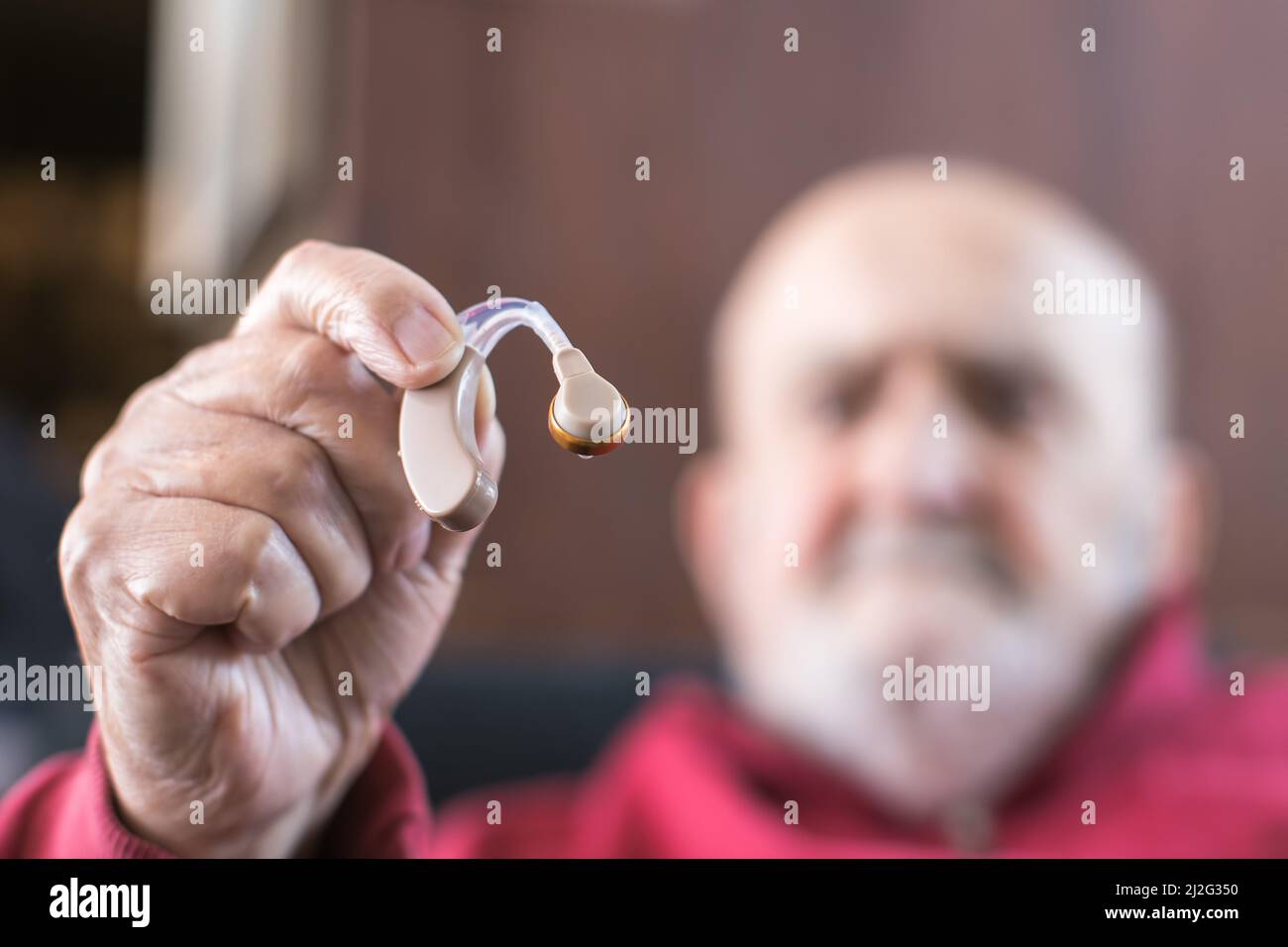 Alter Mann, der Hörgerät in der Hand hält Stockfoto