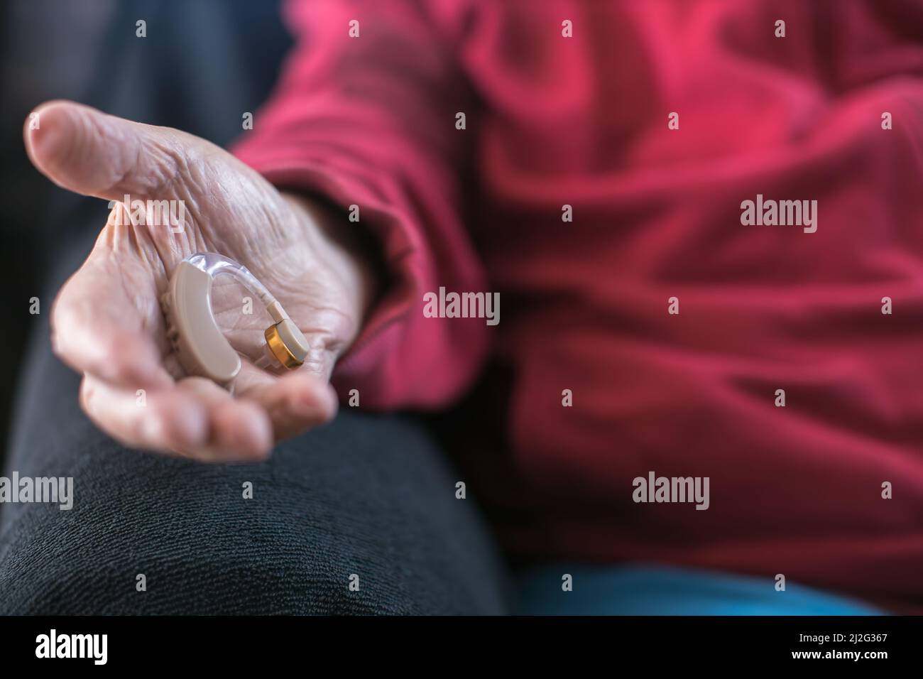 Hörgerät mit der Hand älterer Menschen Stockfoto
