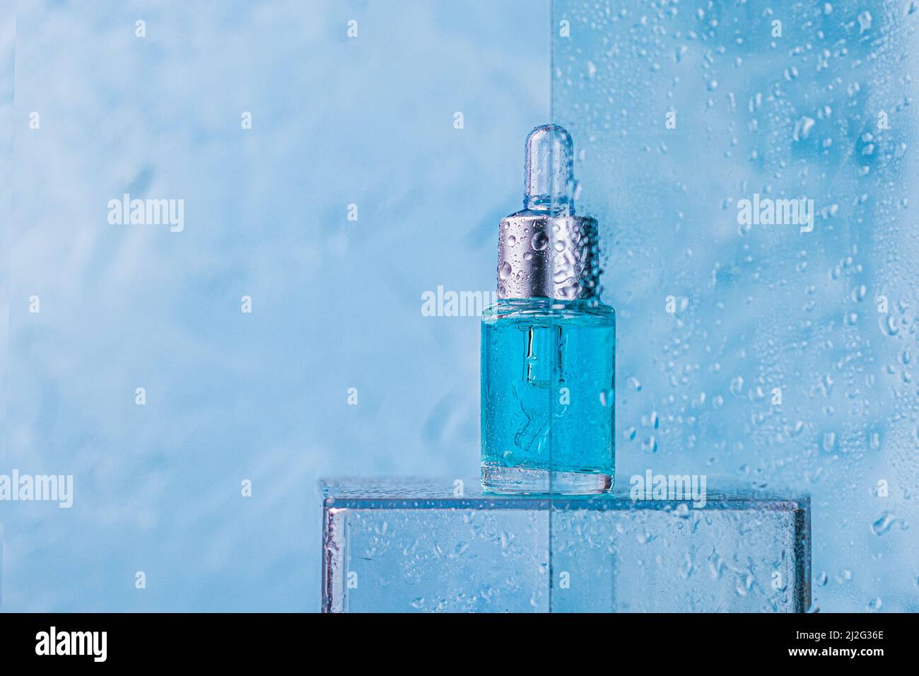 Lotion, Öl oder Serum in blauer Tropfflasche aus Glas mit Wassertropfen mit Kopierraum. Spa-Produkt. Bio, Bio, Naturkosmetik. Schönheit, Ski Stockfoto