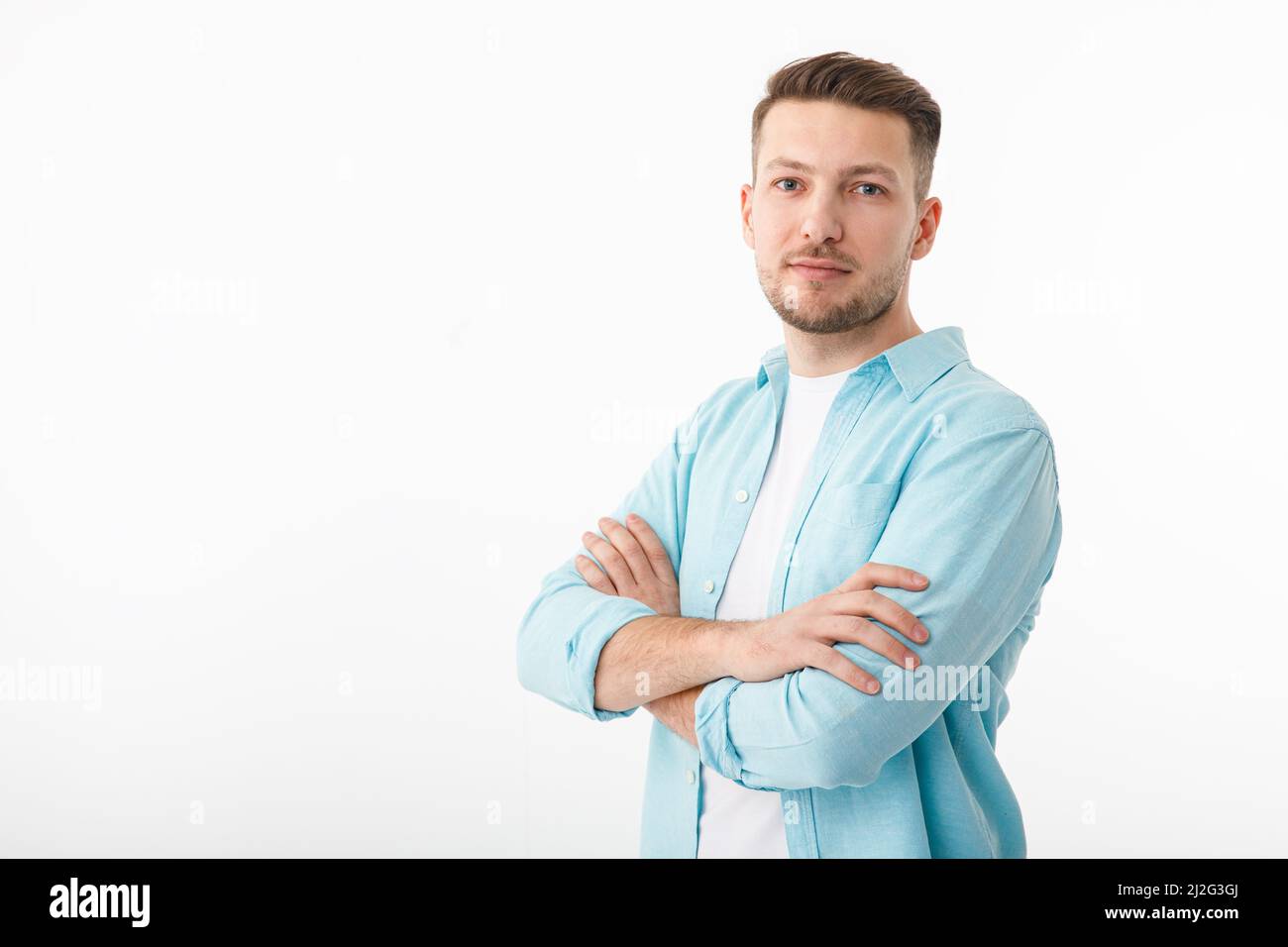 Porträt eines fröhlichen jungen Mannes in einem weißen T-Shirt auf weißem Hintergrund. Der Typ steht und schaut auf die Kamera und lächelt. Stockfoto