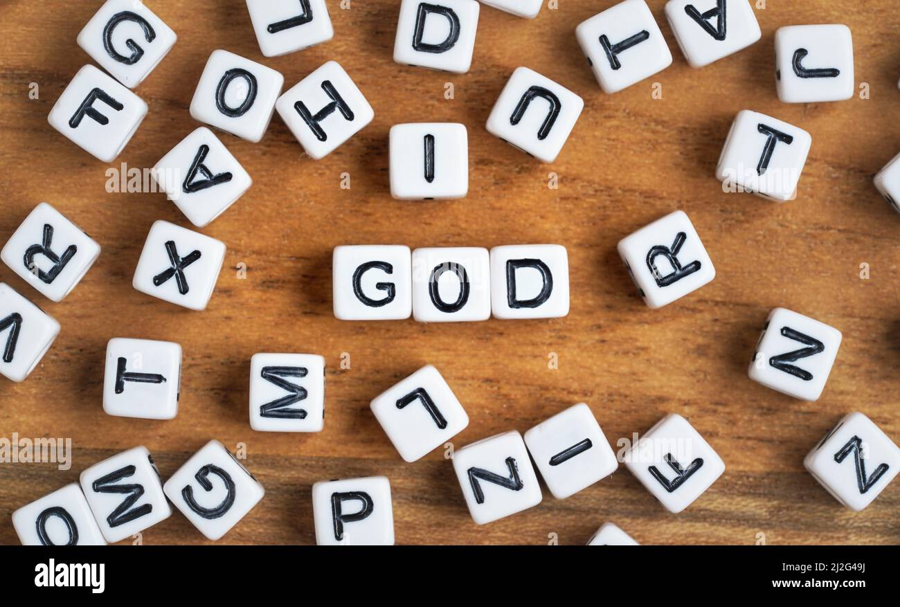 Kleine weiße und schwarze Perlenwürfel auf Holzbrett, Buchstaben in der Mitte buchstabieren GOTT, Religion Konzept Stockfoto