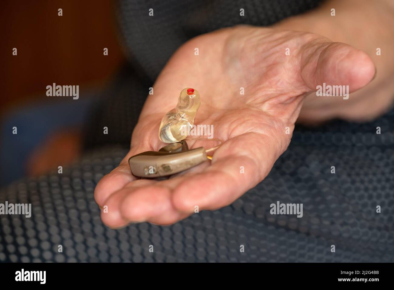 Ältere ältere Frau, die ein Hörgeräteinstrument in der Hand hält, Nahaufnahme Stockfoto
