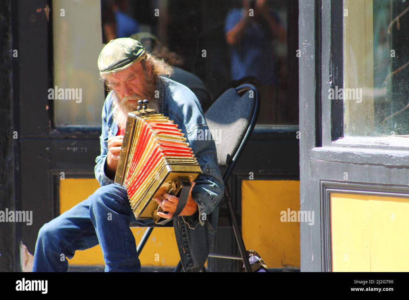 Ein Straßenmusiker, der ein Akkordeon in einer Tür spielt, Water Street, St. John's, NL. Stockfoto