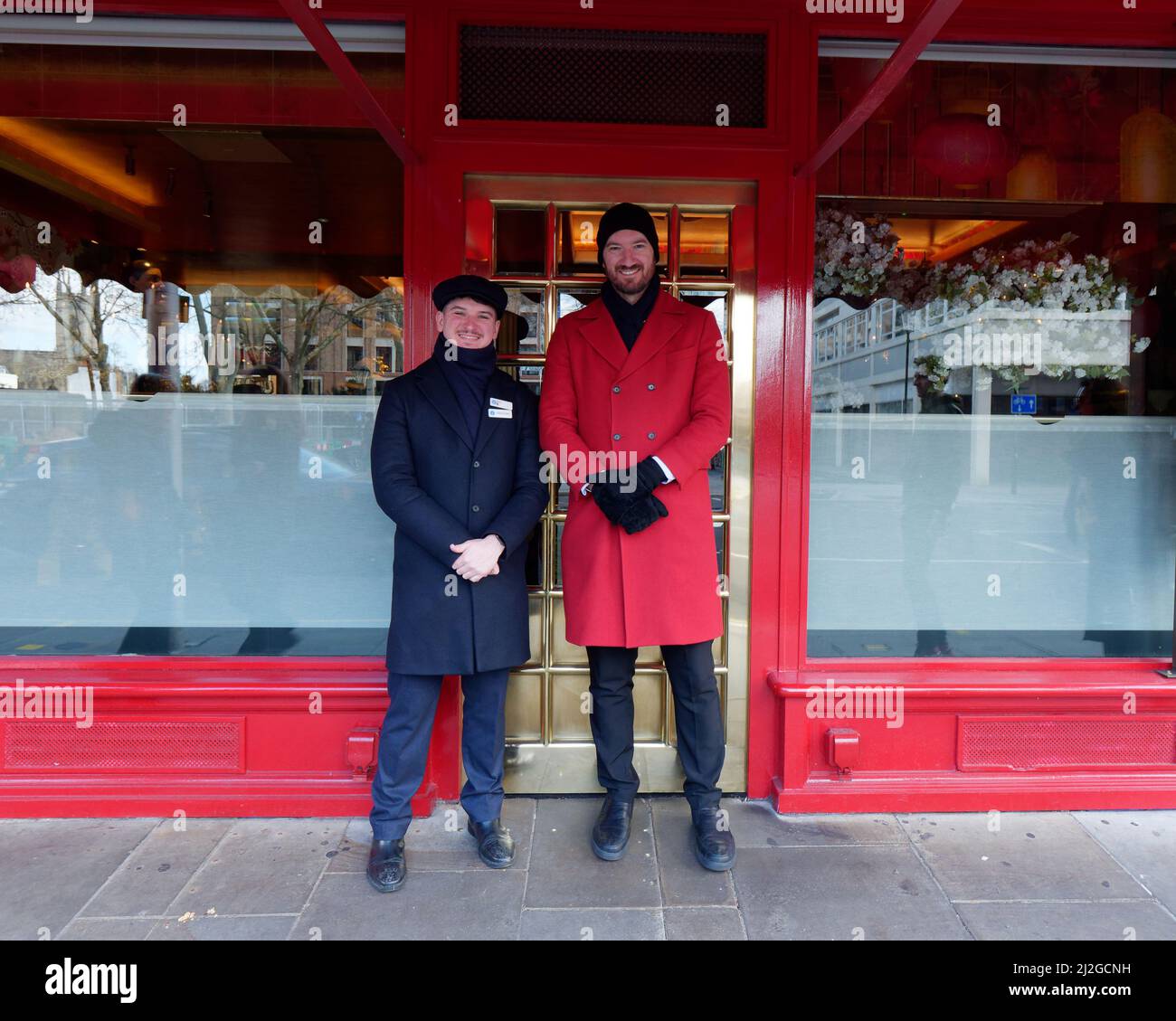 London, Greater London, England, 12 2022. März: Lächelnde Türsteher in Winterkleidung vor einem Restaurant an der Kings Road Stockfoto