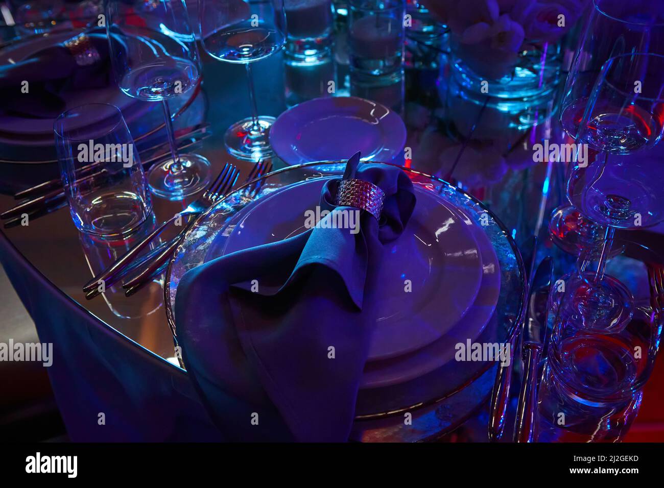 Tabelle in violettem Licht eingerichtet. Bereit für die Veranstaltung. Flacher freiheitsgrad Stockfoto